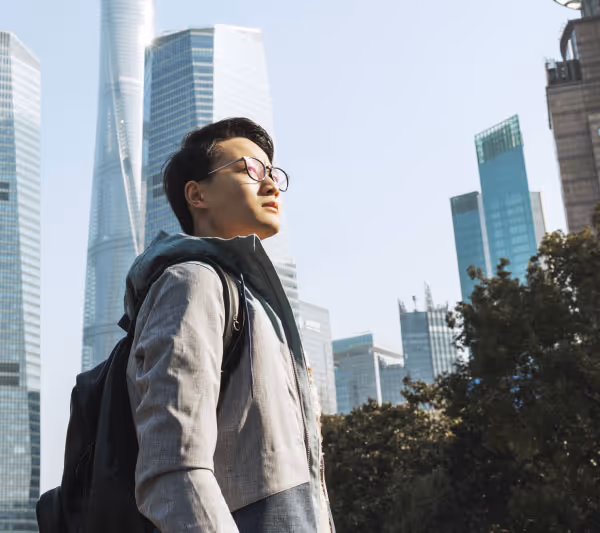 Man standing in the city, looking up at the sun