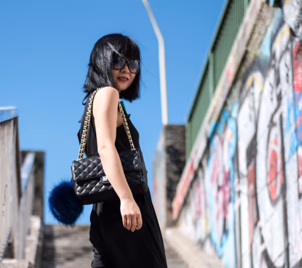 Woman posing in black dress with black purse