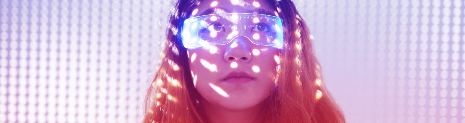 Young woman with flowing hair wearing illuminated futuristic glasses with light dots on her face.
